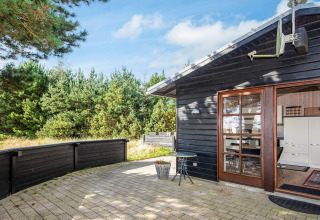 Udendørs terrasse ved Seaside Escape i Ho Bay, Danmark, omgivet af fyrretræer og natur.