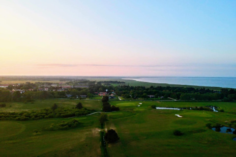 Zonsondergang vanaf de ‘Seaside Escape in Ho Bay’ hut in Denemarken, met zicht op golf en kustlijn.