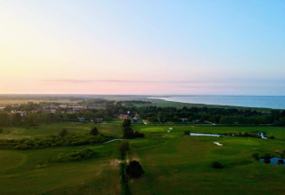 Solnedgang over det smukke Ho Bugt-område, set fra sommerhus ved stranden i Danmark, nær grøn golfbane.
