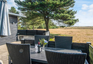 Terrasse extérieure à 'Seaside Escape in Ho Bay', Danemark, avec table noire, chaises et vue naturelle.