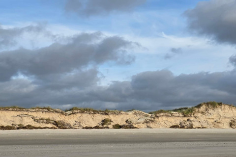 Photo of the beach and dunes from Seaside Escape in Ho Bay, Denmark, with a cloudy sky above.