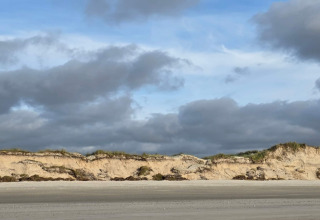 Foto van het strand en de duinen bij Seaside Escape in Ho Bay, Denemarken, onder een grijze lucht.