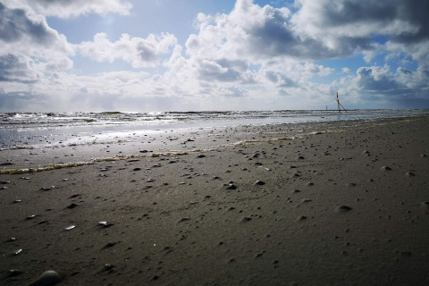 Vue sur la plage et la mer à Ho Bay, Danemark, avec nuages et soleil près du chalet Seaside Escape.