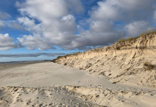 Spiaggia sabbiosa e dune vicino alla cabina 'Seaside Escape' a Ho Bay, Danimarca, sotto cielo nuvoloso.