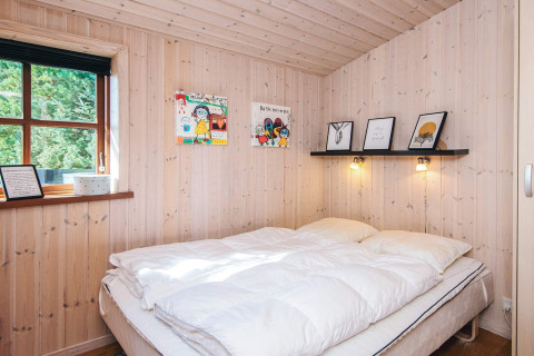 Camera accogliente nella baita Seaside Escape a Ho Bay, Danimarca, con pannelli in legno e letto doppio.