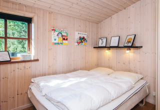Cozy bedroom at Seaside Escape cabin in Ho Bay, Denmark, with light wood paneling and double bed.