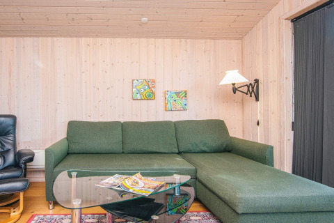 Living room with green sofa, glass coffee table, magazines, wall art in Seaside Escape in Ho Bay, Denmark.