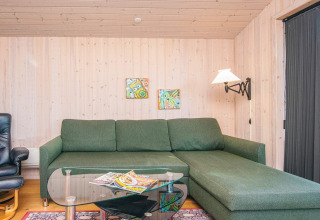 Living room with green sofa, glass coffee table, magazines, wall art in Seaside Escape in Ho Bay, Denmark.
