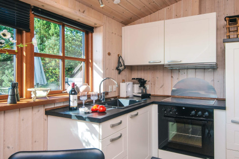 Cucina accogliente con pannelli in legno, grandi finestre e moderni elettrodomestici a Seaside Escape.
