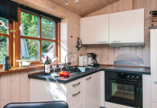 Gezellige houten keuken met grote ramen, zwarte werkbladen en moderne toestellen bij Seaside Escape.