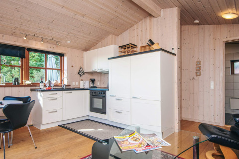 Cocina moderna en una cabaña de Seaside Escape en Ho Bay, Dinamarca, con paredes de madera clara y ventana.
