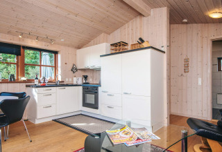 Moderne køkken i en træhytte ved Seaside Escape i Ho Bay, Danmark, med store vinduer og lyst interiør.