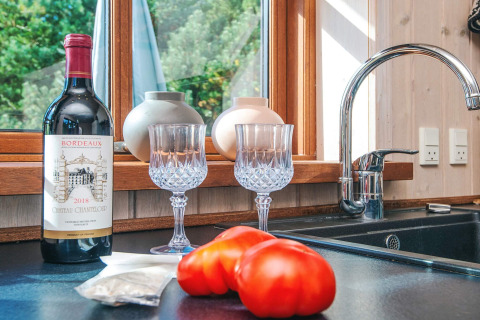 Keukenblad met rode wijn, twee wijnglazen en tomaten met raamzicht in Seaside Escape in Ho Bay, Denemarken.
