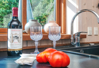 Küchentheke mit Rotwein, zwei Weingläsern, Tomaten und Fensterblick in der Seaside Escape in Ho Bay, Dänemark.