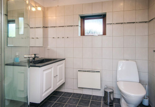 Moderne badeværelse i Seaside Escape i Ho Bay, Danmark, med toilet, håndvask og bruseniche.