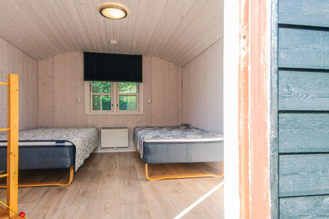 To enkeltsenge i et lyst træindrettet værelse i kabinen 'Seaside Escape in Ho Bay', Danmark.