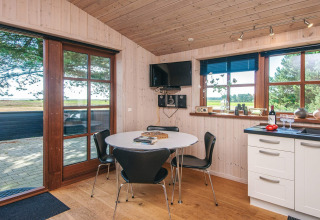 Lyst køkken og spiseplads med udsigt over naturen i hytten 'Seaside Escape in Ho Bay', Danmark.