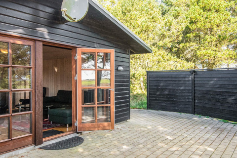 Outdoor patio of a black wood cabin with open double doors and forest view, Seaside Escape in Ho Bay
