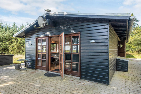 Black wooden cabin called 'Seaside Escape in Ho Bay' with patio doors, located in Denmark.