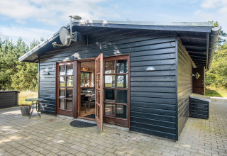 Black wooden cabin called 'Seaside Escape in Ho Bay' with patio doors, located in Denmark.