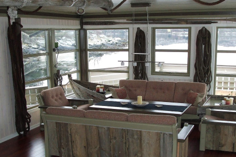 Sala de estar en la casa flotante '38508-FISKHOLMEN' en Dinamarca con muebles rústicos y vistas al agua.