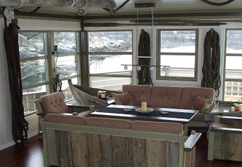 Woonkamer op woonboot ‘38508-FISKHOLMEN’ in Denemarken met landelijke meubels en uitzicht op het water.