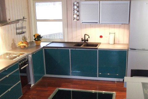 Cocina moderna en la casa flotante 38508-FISKHOLMEN en Dinamarca con gabinetes verdes y ventana.