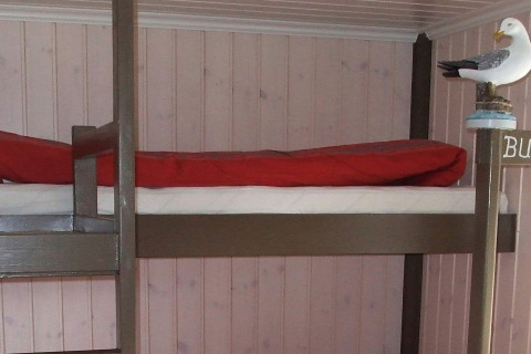 Litera con manta roja y figura de gaviota en la casa flotante 38508-FISKHOLMEN en Dinamarca, pared de madera.