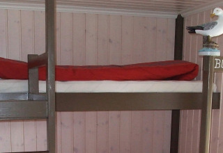 Litera con manta roja y figura de gaviota en la casa flotante 38508-FISKHOLMEN en Dinamarca, pared de madera.