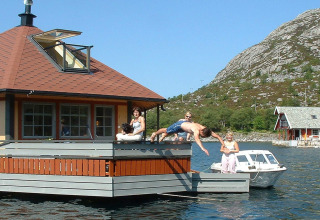 People relaxing on the houseboat 38507-SJØSTJERNEN in Denmark while a man dives into the water.