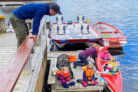 Family on a dock by houseboat 38507-SJØSTJERNEN in Denmark, children in life jackets and a kayak.