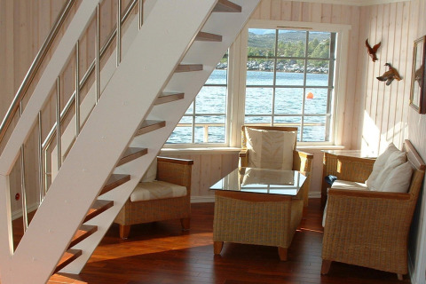 Bright corner of houseboat «38507-SJØSTJERNEN» in Denmark, featuring cozy chairs and scenic water view.