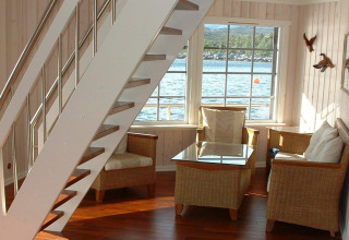 Bright corner of houseboat «38507-SJØSTJERNEN» in Denmark, featuring cozy chairs and scenic water view.