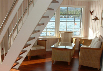 Bright corner of houseboat «38507-SJØSTJERNEN» in Denmark, featuring cozy chairs and scenic water view.
