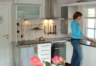 Woman cooking in the modern kitchen of houseboat 38507-SJØSTJERNEN, docked in Denmark.