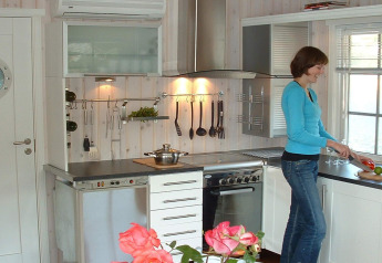 Woman cooking in the modern kitchen of houseboat 38507-SJØSTJERNEN, docked in Denmark.