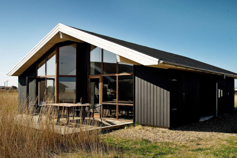 Modern 8-persoons vakantiehuis in Ulfborg, Denemarken, met grote ramen en zwarte houten buitenkant.