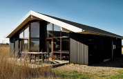 Chalet moderno per 8 persone a Ulfborg, Danimarca, con ampie finestre e facciata in legno scuro.