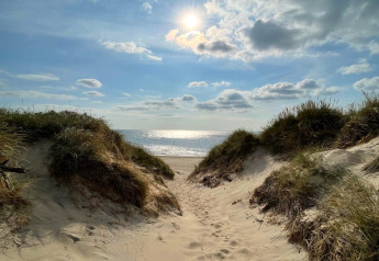 Solskinnet strandudsigt fra klitter ved Ulfborg, Danmark, set fra feriehusets sti ned til havet.