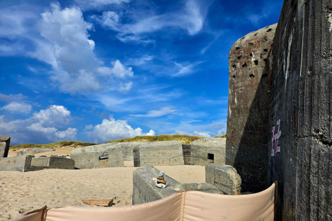 Vecchi bunker di cemento su una spiaggia sabbiosa con cielo blu a Ulfborg, Danimarca, vista vacanza.