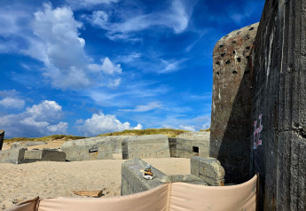Vecchi bunker di cemento su una spiaggia sabbiosa con cielo blu a Ulfborg, Danimarca, vista vacanza.