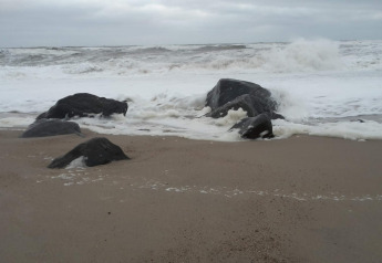 Udsigt over bølger, der slår ind mod klipper på stranden ved 8-personers feriehus i Ulfborg, Danmark.