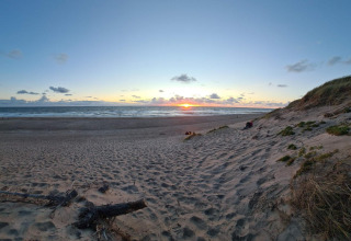 Zonsondergang aan het strand met zicht vanaf een duin bij het 8-persoons vakantiehuis in Ulfborg, Denemarken.