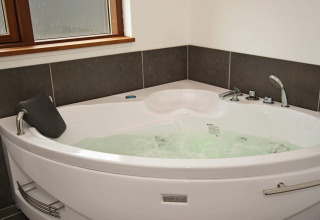 Corner Jacuzzi bathtub with bubbling water in a bathroom at the 8 person holiday home in Ulfborg, Denmark.