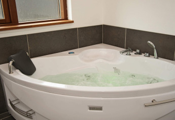 Vasca idromassaggio angolare con acqua frizzante nel bagno della casa vacanze per 8 a Ulfborg, Danimarca.