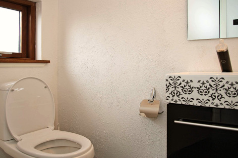 Badeværelse med åben toilet, papirholder og moderne vask på 8-personers feriehus i Ulfborg, Danmark.