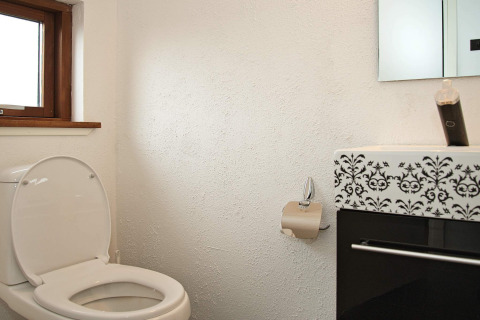 Badkamer met open toilet, toiletrolhouder en moderne wastafel in 8-persoons vakantiechalet in Ulfborg, Denemarken.