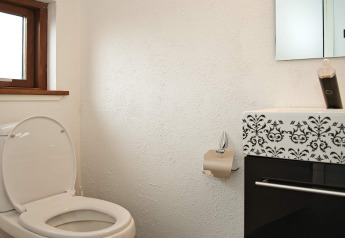 Badezimmer mit offenem WC, Toilettenpapierhalter und stilvollem Waschbecken im Ferienhaus in Ulfborg.
