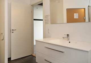 Modern bathroom with white sink, mirror, and open door in an 8-person holiday home in Ulfborg, Denmark.