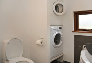Salle de bain dans une maison de vacances à Ulfborg, Danemark, avec toilettes, lave-linge et fenêtre.